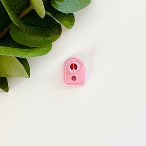 May include: A pink plastic nozzle with a round opening and a small hole in the center.