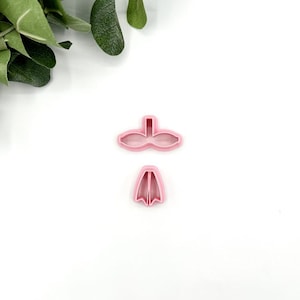 May include: Two pink plastic cookie cutters shaped like a duck's head and foot.