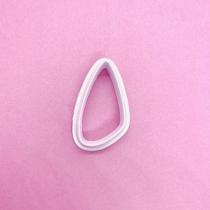 May include: White plastic cookie cutter shaped like a teardrop.