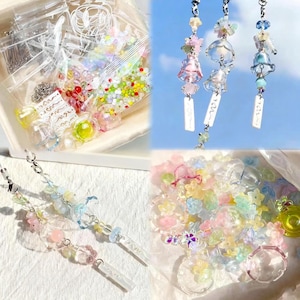 May include: A collection of colorful craft supplies, including beads, charms, and earring components. The image shows various clear plastic bags filled with small, decorative items in pastel colors. Several finished earrings with floral and bell-shaped charms are also displayed.