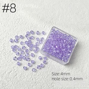 May include: A clear plastic container filled with small, faceted, lavender beads. Some beads are scattered around the container. The text "#8" is in the upper left corner. The text "Size: 4mm" and "Hole size: 0.4mm" are in the lower right corner.