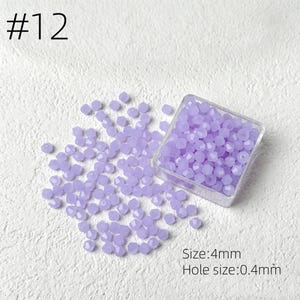 May include: A collection of faceted, light purple beads, scattered on a white surface, with some contained in a clear square container. The text "#12" is in the upper left corner. The text "Size: 4mm" and "Hole size: 0.4mm" are in the lower right corner.
