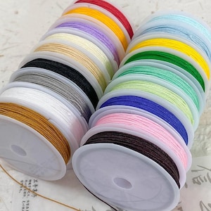 Könnte beinhalten: Ein Set aus drei Keramikbechern mit gesprenkelter, matter Oberfläche. Die Becher sind in Creme-, Hellgrau- und Dunkelgrautönen gehalten. Jeder Becher hat ein schlichtes, minimalistisches Design und einen abgerundeten Griff.