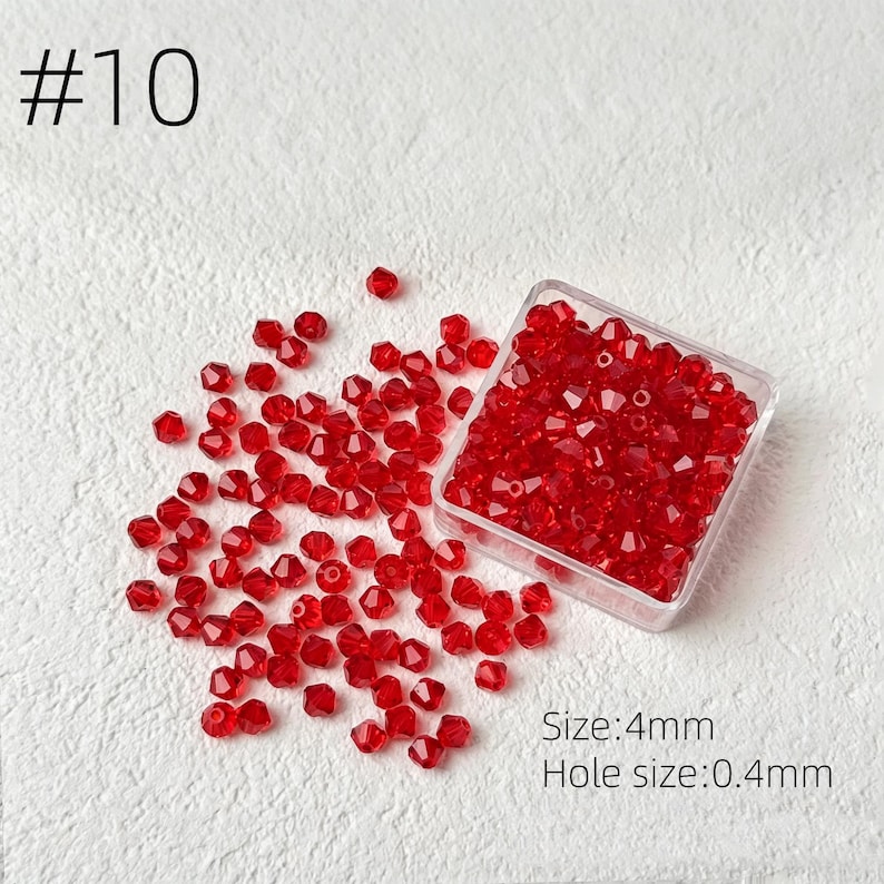 May include: A collection of small, faceted red beads, some scattered and some contained in a clear plastic box. The beads are 4mm in size with a 0.4mm hole. The number "#10" is printed in the upper left corner.