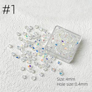 May include: Clear, iridescent crystal beads scattered on a white surface, with some contained in a clear square container. The text "#1" is in the upper left corner. The text "Size: 4mm" and "Hole size: 0.4mm" are in the lower right corner.