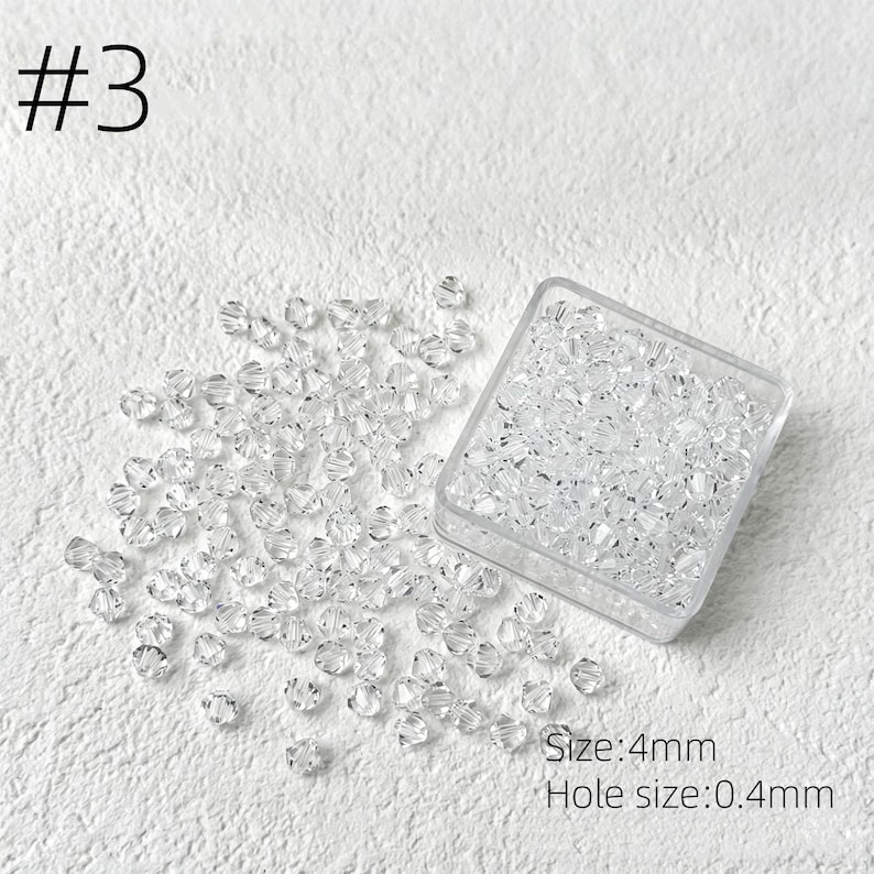 May include: Clear crystal beads, size 4mm, are scattered on a white surface, with some contained in a clear square container. The text "#3" is in the upper left corner. The text "Size: 4mm" and "Hole size: 0.4mm" are in the lower right corner.