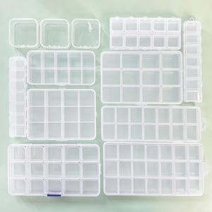 Puede incluir: Una colección de organizadores de almacenamiento de plástico transparente en varias formas rectangulares y cuadradas, con múltiples compartimentos internos y tapas con bisagras para clasificar objetos pequeños y materiales.