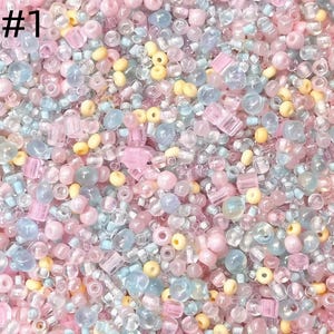 Peut inclure: Gros plan sur un mélange de petites perles de différentes formes et tailles. Les perles sont dans des tons de rose, de bleu, de jaune et de transparent. L'image porte le numéro "#1" en haut à gauche.