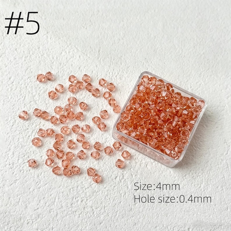 May include: A collection of small, faceted, peach-colored beads, some scattered and some contained in a clear square container. The text "#5" is in the upper left corner. The text "Size: 4mm" and "Hole size: 0.4mm" are in the lower right corner.