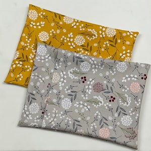May include: Two fabric swatches with floral patterns. The top swatch is yellow with white flowers and the bottom swatch is gray with white and pink flowers.