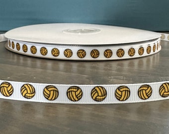 May include: White ribbon with a repeating pattern of yellow volleyball designs. The ribbon is rolled up on a white spool.