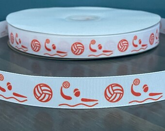 May include: White ribbon with a repeating pattern of orange water polo players and volleyballs. The ribbon is rolled up on a spool.