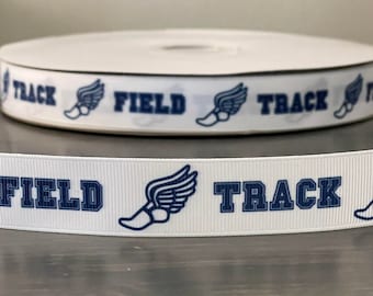 May include: White ribbon with the words "TRACK" and "FIELD" in navy blue, along with a winged shoe graphic. The ribbon is rolled up, with a close-up view of the design.