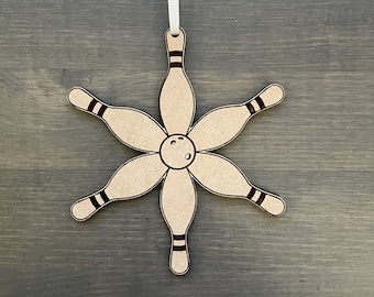 May include: A wooden ornament shaped like a bowling pin with a bowling ball in the center. The ornament is brown and has a white ribbon attached to the top.