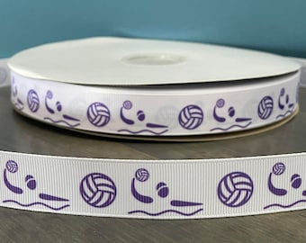 May include: White ribbon with a repeating pattern of purple volleyball players and volleyballs. The ribbon is on a wooden surface.