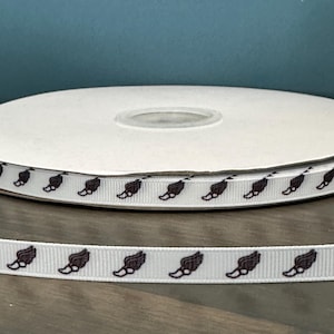 May include: White ribbon with a repeating pattern of brown running shoe prints. The ribbon is wound around a white spool.