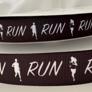 May include: Brown ribbon with white text that says "RUN" and a silhouette of a runner. The ribbon is folded in half, showing the design on both sides.