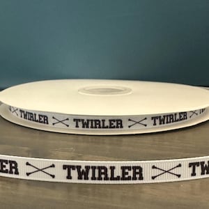 May include: White ribbon with the text "TWIRLER" printed in black with a pair of crossed batons between each word.