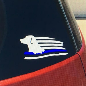 May include: White silhouette of a dog running with a thin blue line across the bottom of the image. The dog is running in front of a white and blue American flag.