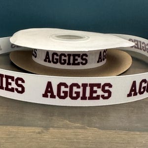 May include: White ribbon with the word "AGGIES" printed in maroon letters.