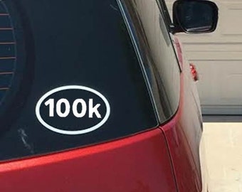 May include: A red car with a white oval sticker that says "100k" on the rear window.