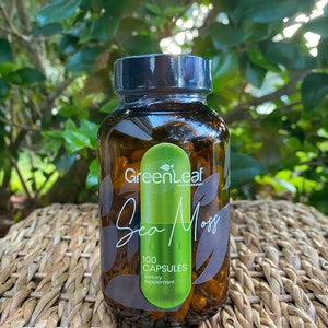 May include: A brown glass bottle with a black lid and a green label that says "GreenLeaf Nature Solutions Sea Moss 100 Capsules Dietary Supplement".