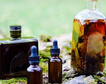 May include: Four glass bottles with dark liquid inside. The bottles have cork and dropper tops. The bottles are sitting on a mossy log.