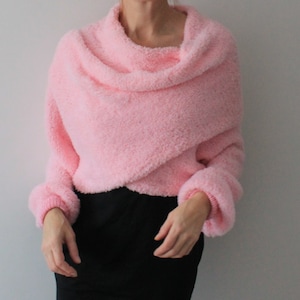 May include: A pink fuzzy sweater with a cowl neck and long sleeves.