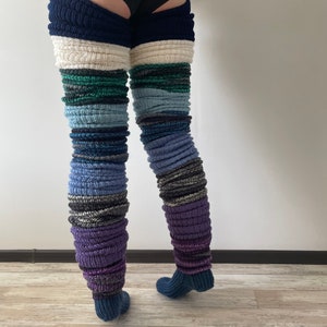 May include: A pair of thigh-high leg warmers made of knitted fabric in various shades of blue, green, purple, and white. The leg warmers are layered on top of each other, creating a unique and colorful look.