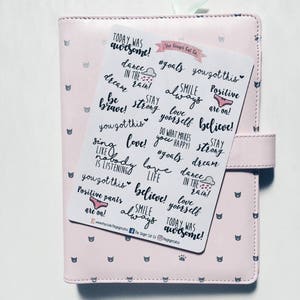 May include: A sheet of stickers with motivational quotes and illustrations. The stickers feature phrases like "Today was awesome!" and "You got this!" in black script on a white background. Some stickers have pink accents, including a pair of pink underwear with the text "Positive pants are on!"