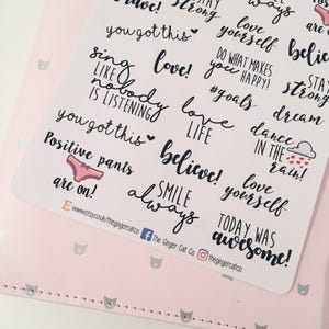 May include: A sheet of white stickers with black and pink lettering. The stickers feature positive affirmations and motivational quotes such as "love yourself", "believe", "smile always", "you got this", "dance in the rain", and "positive pants are on!"