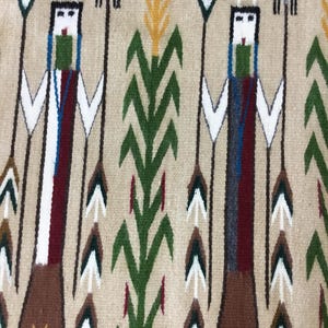 May include: A woven textile featuring a repeating pattern of stylized figures and plant motifs. The figures have white faces, green and blue accents, and hold spears. The background is tan, with green, yellow, and brown plant designs.