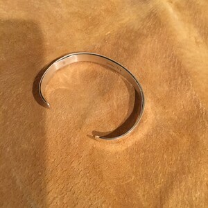 May include: A silver bangle bracelet with a smooth, polished finish.