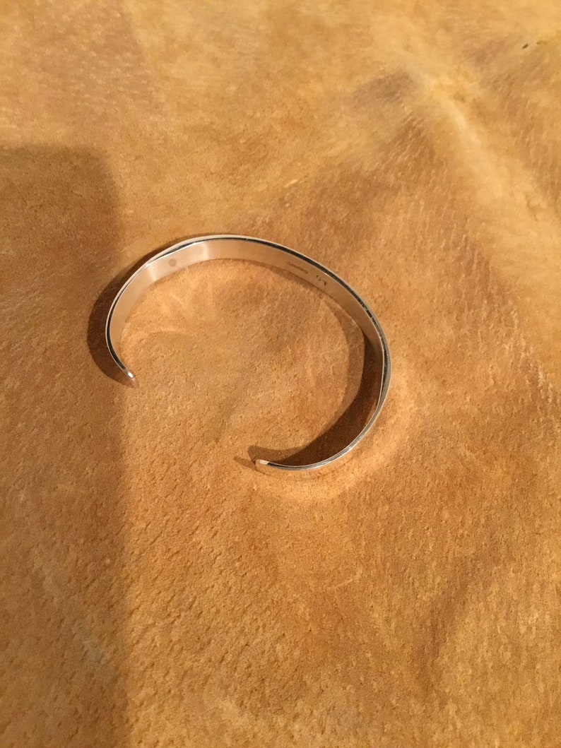 May include: A silver bangle bracelet with a smooth, polished finish.