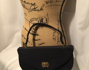 May include: A black satin evening bag with a gold clasp and a short handle.