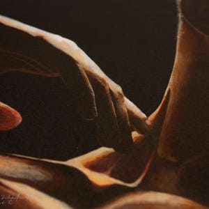 May include: A close-up of two hands intertwined, with the skin tones ranging from light to dark brown. The image is lit from the side, creating a dramatic contrast between the light and dark areas.