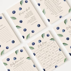 May include: A set of baby shower game cards featuring a blueberry and leaf motif. The cards include games such as "Pacifier Hunt," "Baby Bingo," and "Baby Guess." The cards have a cream background with dark blue blueberries and green leaves.