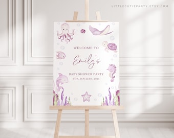 May include: Purple and white welcome sign for a baby shower with the text "Welcome to Emily's Baby Shower Party Sun. Jun 24th, 20xx". The sign features illustrations of an octopus, a stingray, a turtle, a seahorse, a dolphin, a starfish, and seaweed.