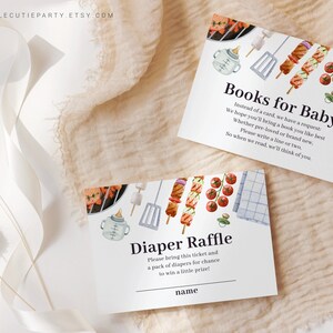 May include: Two white cards with blue text and watercolor illustrations of a grill, skewers, and a baby bottle. The top card says "Books for Baby" and asks guests to bring a book for the baby. The bottom card says "Diaper Raffle" and asks guests to bring a pack of diapers for a chance to win a prize.