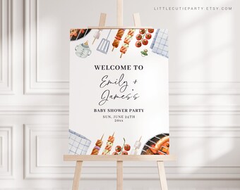 May include: Welcome to Emily + James's Baby Shower Party, Sun. June 24th 20XX. A white sign with a blue and white checkered picnic blanket, a grill, skewers with grilled food, and a baby bottle.