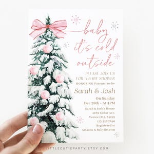 May include: A baby shower invitation card featuring a watercolor illustration of a snow-covered Christmas tree adorned with pink ornaments and a bow. The text reads "baby it's cold outside" and invites guests to celebrate Sarah & Josh.