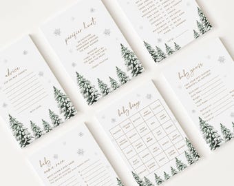 Peut inclure: Ensemble de cartes de jeux pour une baby shower, blanches avec du texte doré et des illustrations de sapins et de flocons de neige. Les jeux incluent Pacifier Hunt, Baby Bingo et Baby Guess, pour une fête hivernale.