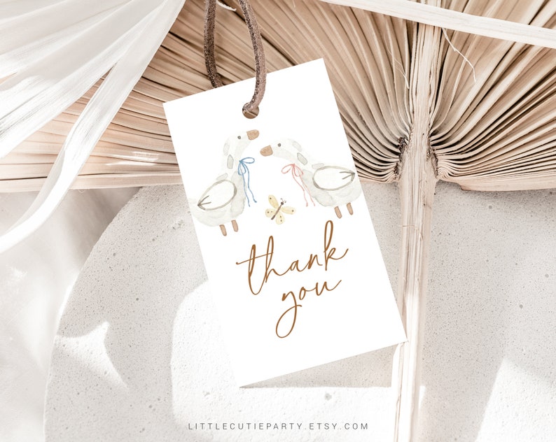 May include: A white thank you tag with a watercolor illustration of two birds with blue and pink ribbons and a yellow butterfly. The text "thank you" is written in brown cursive.