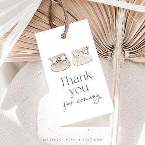 May include: White thank you card with a simple design featuring two small baby shoes and the text "Thank you for coming".