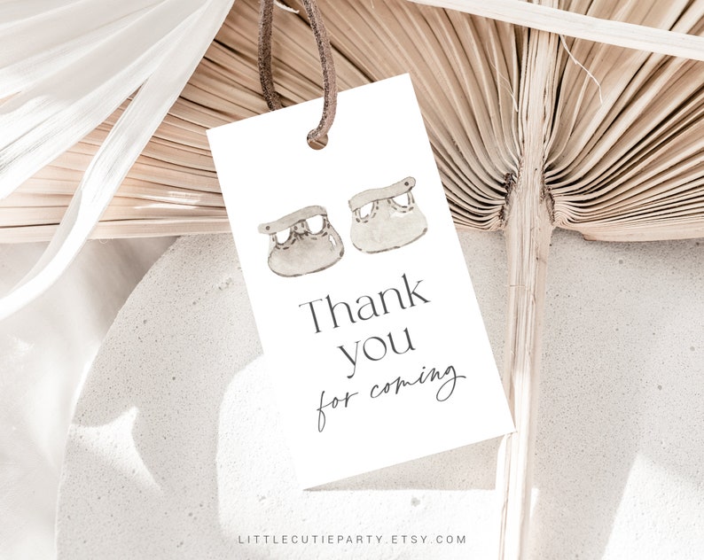 May include: White thank you card with a simple design featuring two small baby shoes and the text "Thank you for coming".
