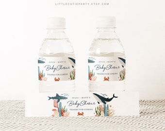 Op de afbeelding: Waterfleslabels met een ontwerp van een blauwe walvis, koraal en een zeester. De labels zeggen "Baby Shower van Julia & Matt Bedankt voor het komen".