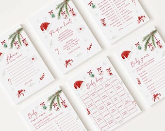 May include: A collection of white cards with red and green Christmas-themed illustrations. The cards feature baby shower game prompts, including "Pacifier Hunt," "Baby Bingo," and "Baby Guess." Festive designs include Santa hats, ornaments, and candy canes.