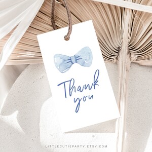 K&ouml;nnte beinhalten: Ein wei&szlig;es Dankesch&ouml;n-Etikett mit einer blauen Aquarell-Fliege und dem Text "Danke".
