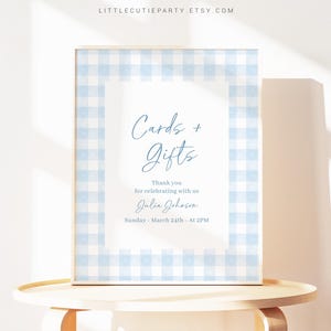 Op de afbeelding: Een blauw en wit gingham-bord met de tekst "Cards + Gifts" en de boodschap "Thank you for celebrating with us Julia Johnson Sunday - March 24th - At 2PM".