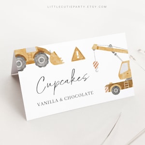 May include: White folded card with watercolor illustrations of construction vehicles, including a bulldozer and crane. The card reads "Cupcakes" with "Vanilla & Chocolate" below. The card is designed for a construction-themed party.
